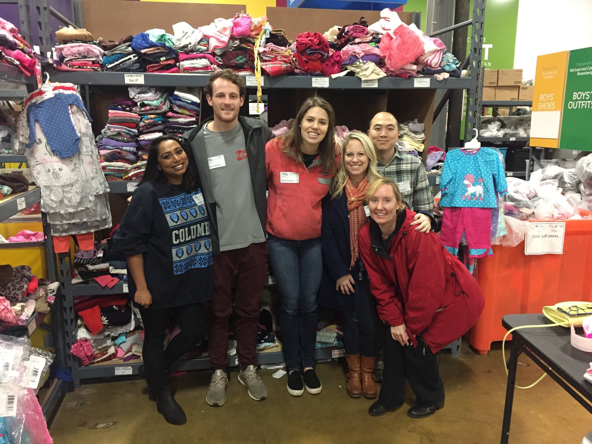 Six employees posing in front of racks of clothing