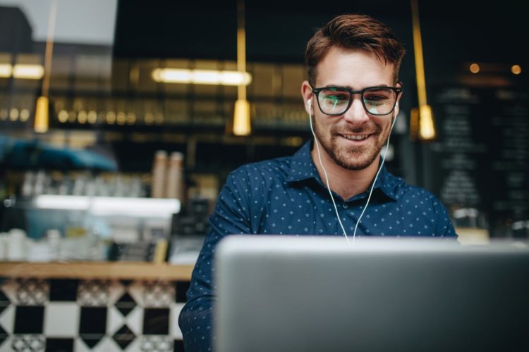 Man using laptop with earbuds