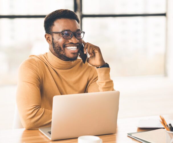 Black man talks on cell phone while working on laptop