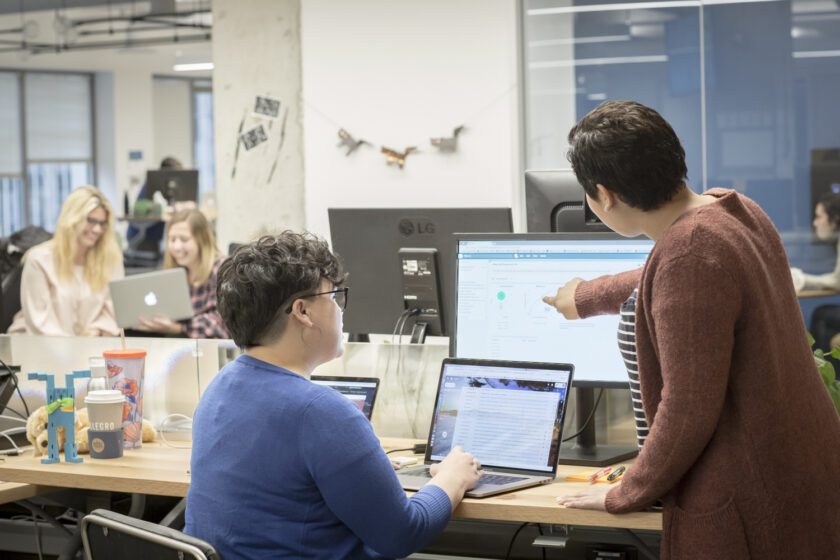 Employees looking at data together on external monitor