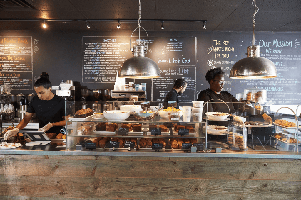 Cafe/bakery counter display with a chalk menu board on the wall.