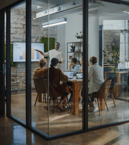 Group of office workers attending a data-powered presentation in a glass conference room