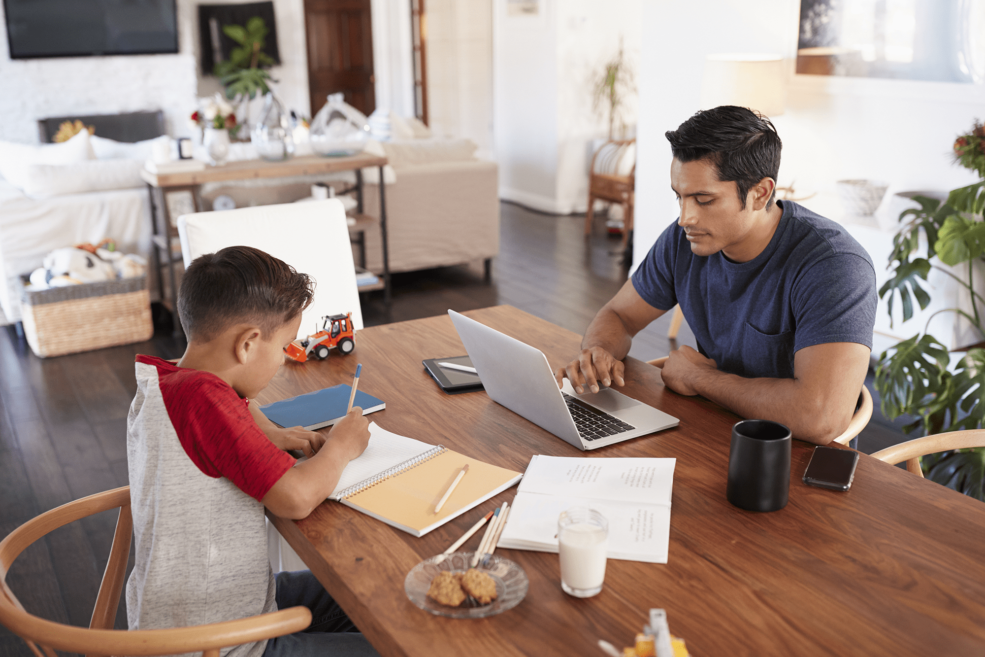 Father and son sharing a table to work and attend school remotely