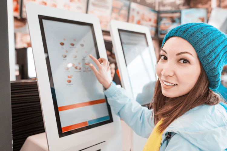 Young person in a beanie hat using a digital touch screen to order food
