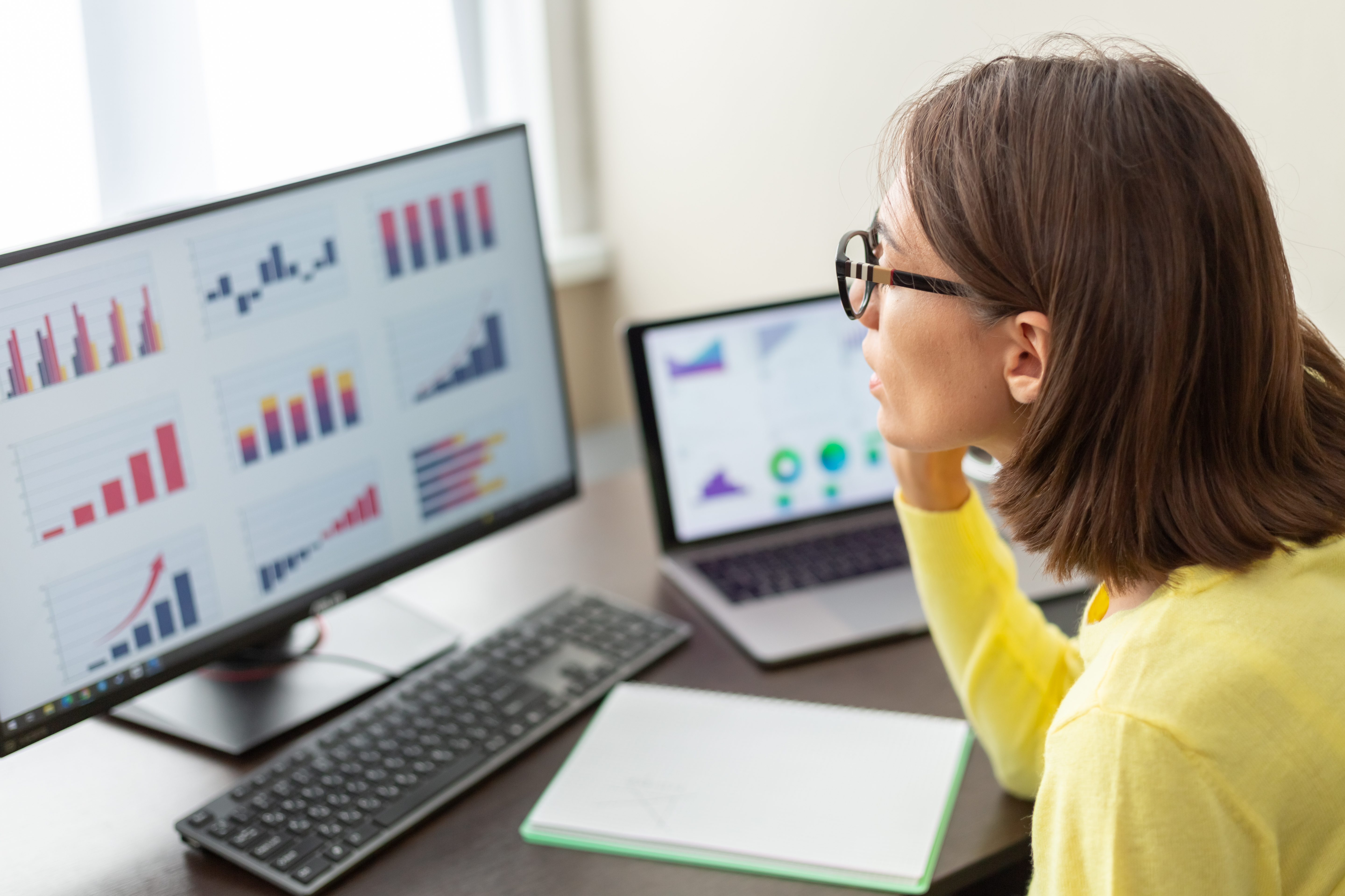 Person with glasses looking over graphs of data on their computer