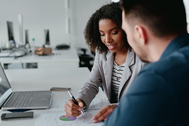 Young Black woman annotating a chart with a colleague