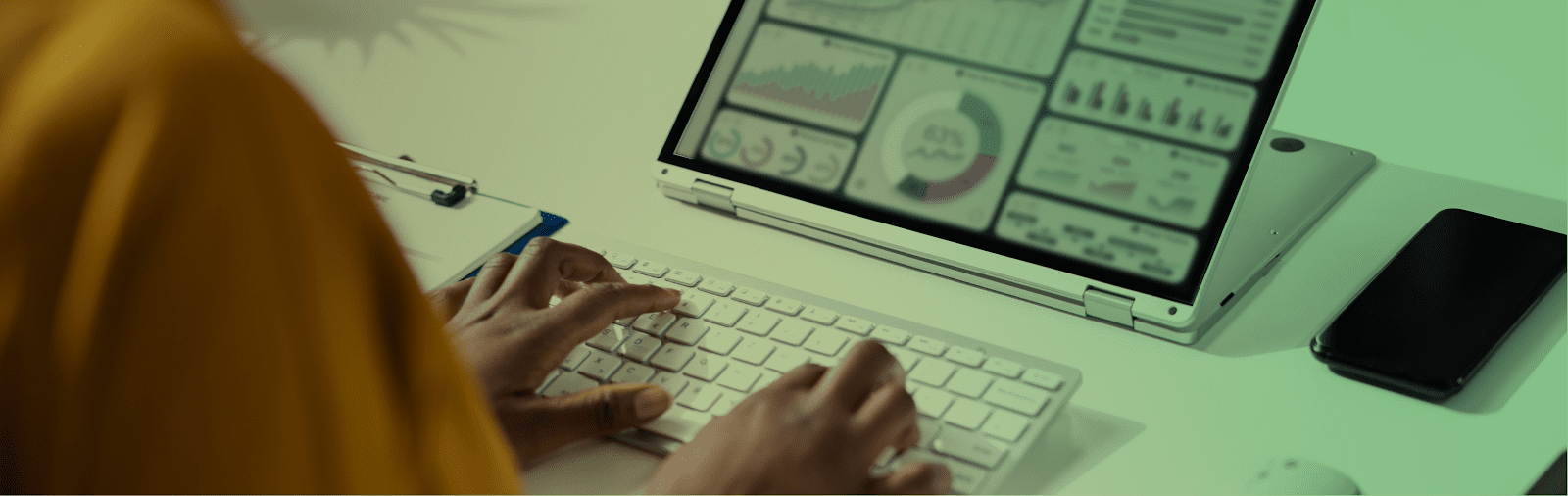 person typing on a wireless keyboard with a data dashboard on their screen