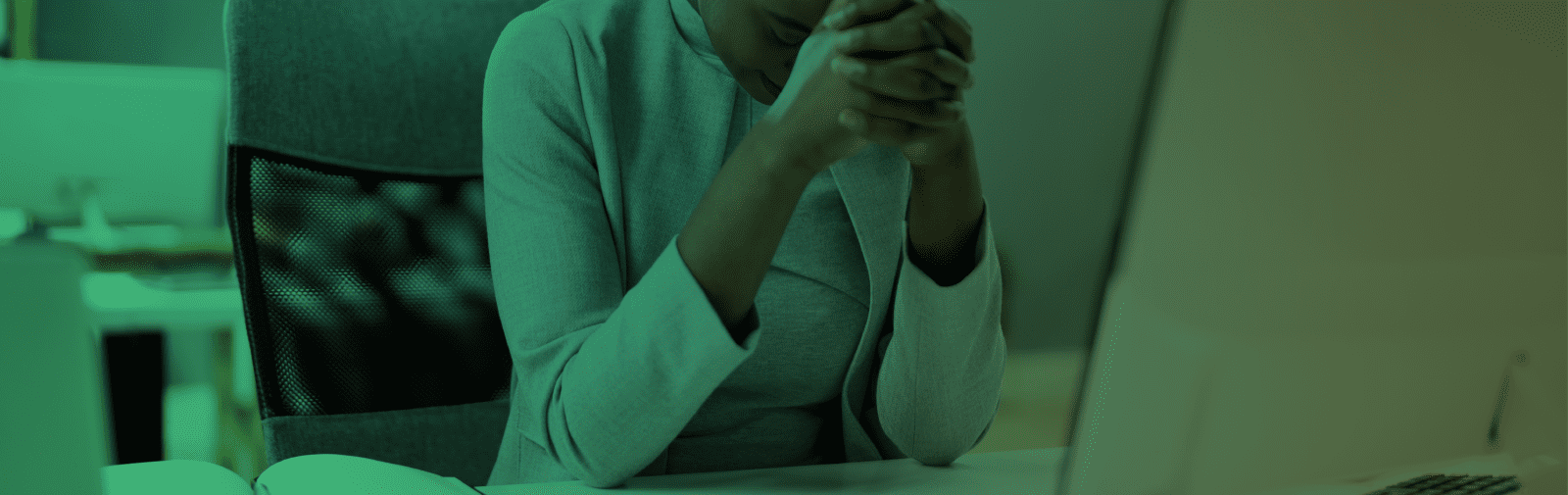 person sitting at their desk with their hands clutched in frustration