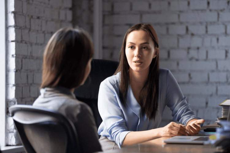 two people sitting in an office at a conference table having a disucssion