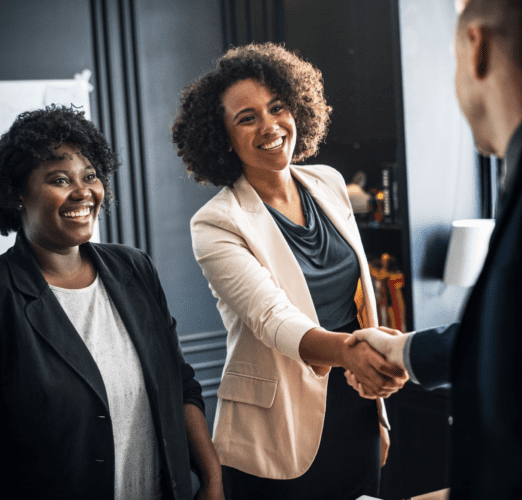 Two Black women greeting a man and shaking hands