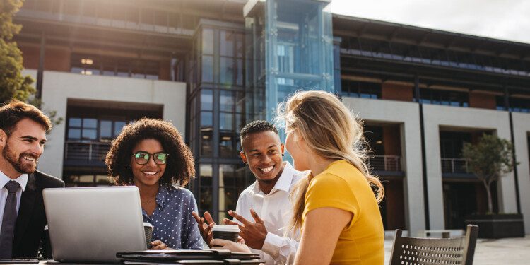 Team of corporate professionals having casual discussion at cafe table. Multi-ethnic business group during coffee break.