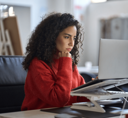 young person at a desk staring intently into a laptop screen